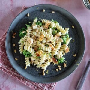 A plate of pasta with Boursin, halloumi, and broccoli. The plate sits on a pink, checkered napkin.