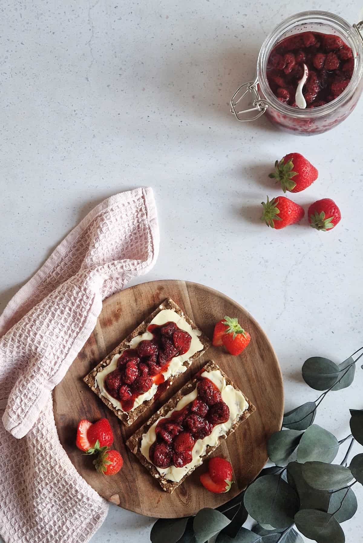 2 pieces of toast on a brown plate, served with butter and strawberry chia jam.