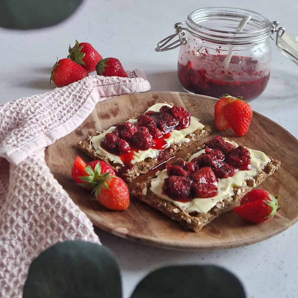Toast with sugar free jam (strawberry chia jam without pectin). The plate is garnished with fresh strawberries.