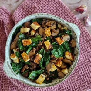 A bowl filled with a cavolo nero salad, with large chunks of halloumi.