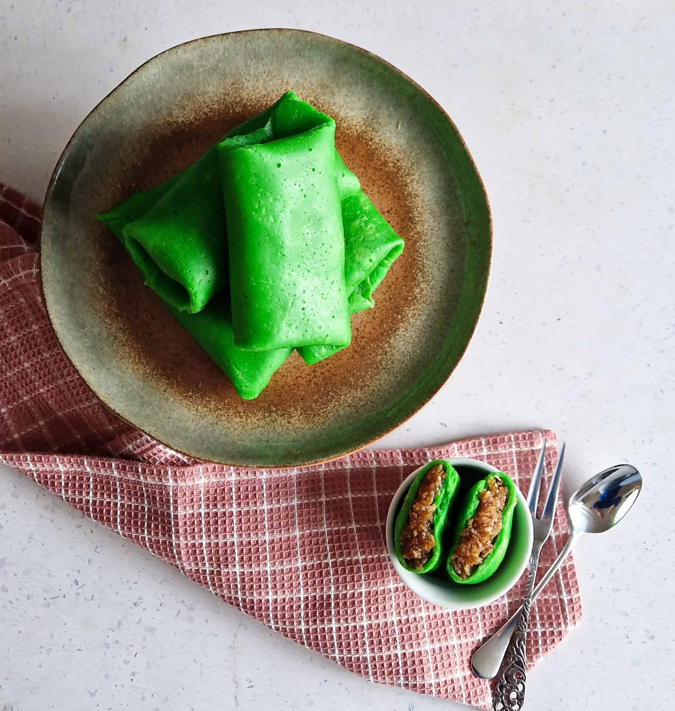 A pile of bright green Indonesian pancakes, on a plate.