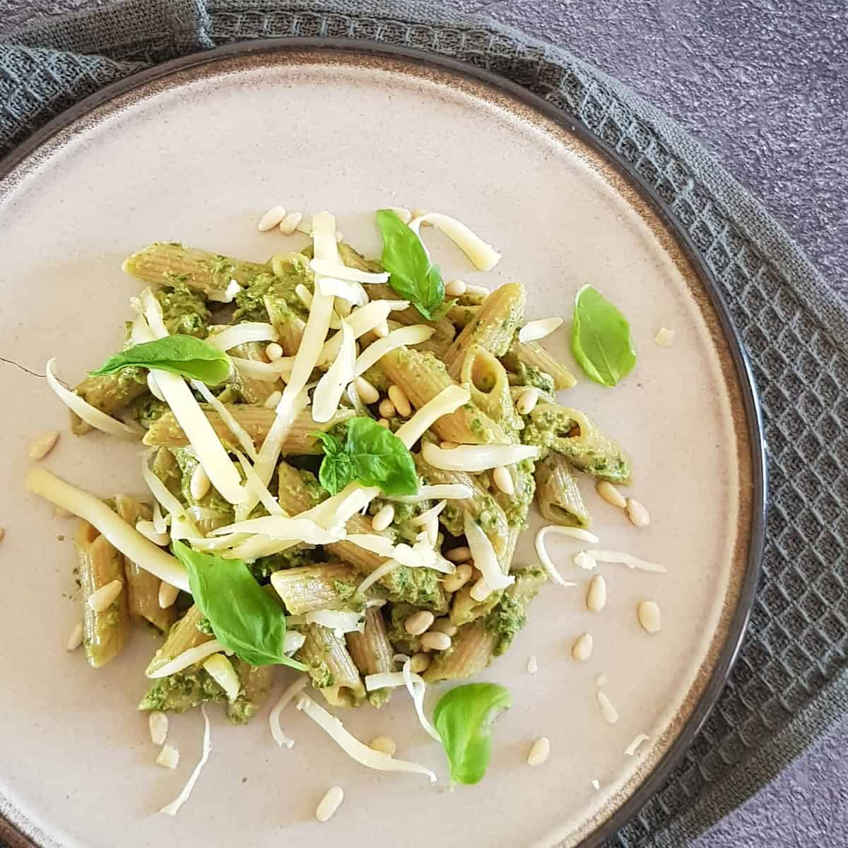 A plate filled with swiss chard pasta, garnished with shavings of Parmesan cheese.