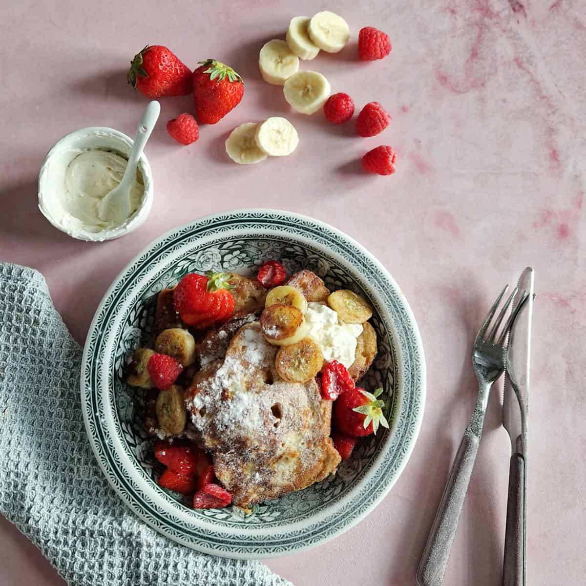 A plate with baked French toast brioche, served with mascarpone and fresh fruits.