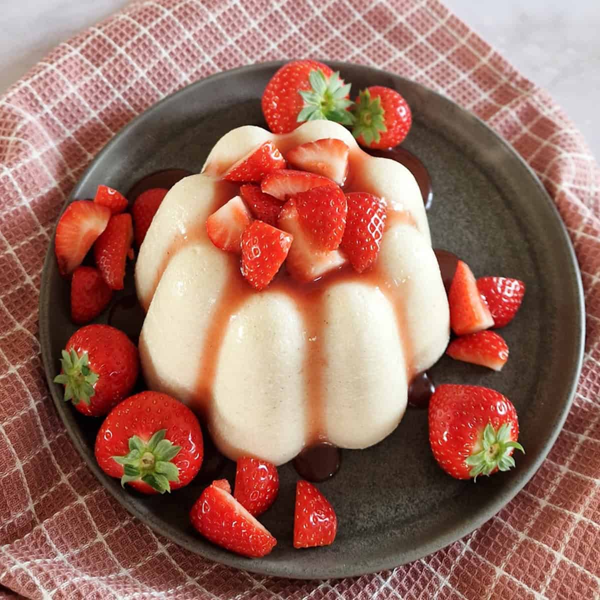 A close-up of a Dutch Griesmeelpudding, served with strawberry sauce and fresh strawberries.