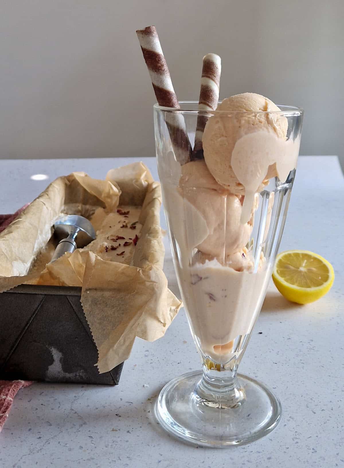 Three scoops of prickly pear ice cream in a sherbet glass, decorated with chocolate straws.