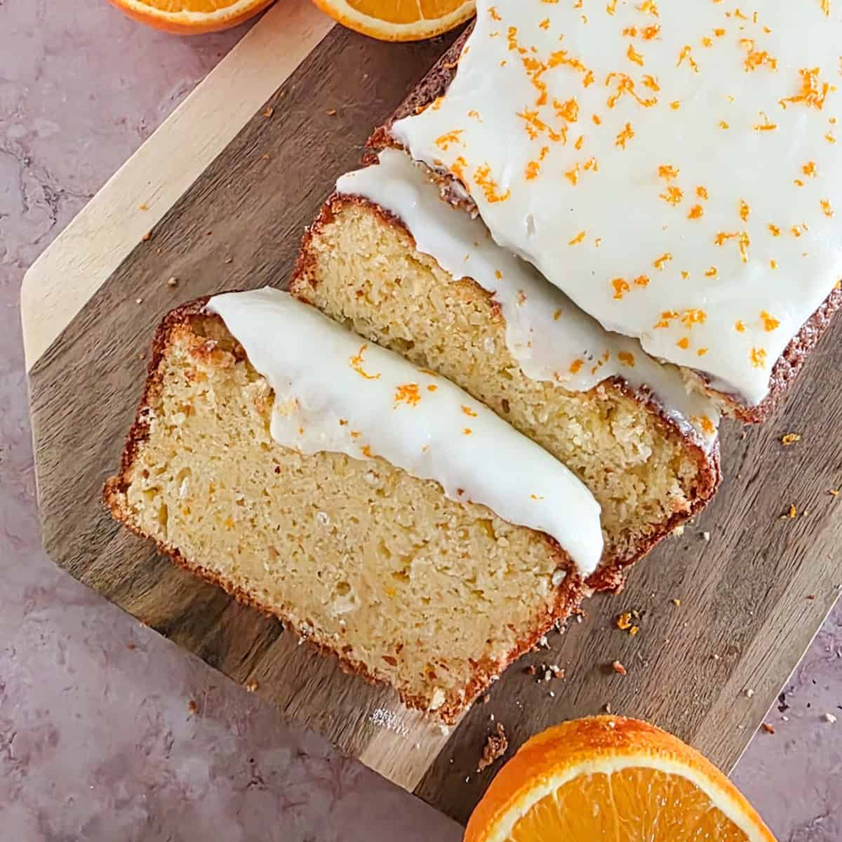 An orange ginger cake, sliced, on a wooden serving platter.