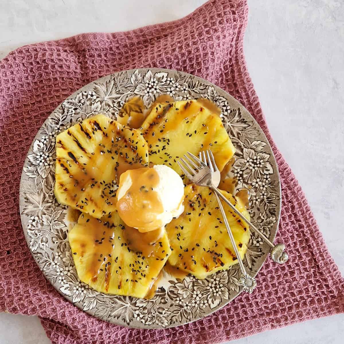 Grilled pineapple on a plate, served with vanilla ice cream and soy caramel sauce.