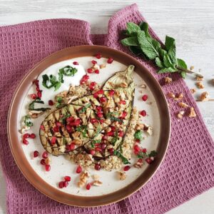A plate of pomegrenate couscous, served with grilled eggplant and fresh mint.