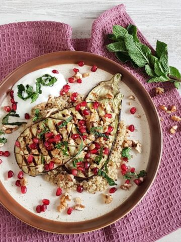 A plate of pomegrenate couscous, served with grilled eggplant and fresh mint.