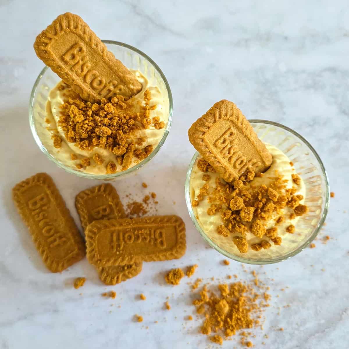 Two glasses filled with a layered Biscoff cookie dessert.