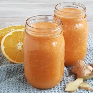 Two Mason Jars filled with a homemade Ginger Carrot Juice with Orange and Apple.