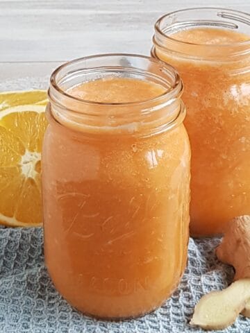Two Mason Jars filled with a homemade Ginger Carrot Juice with Orange and Apple.