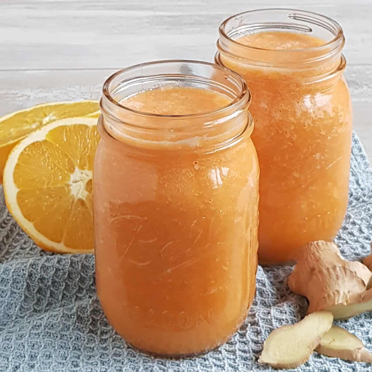 Two Mason Jars filled with a homemade Ginger Carrot Juice with Orange and Apple.